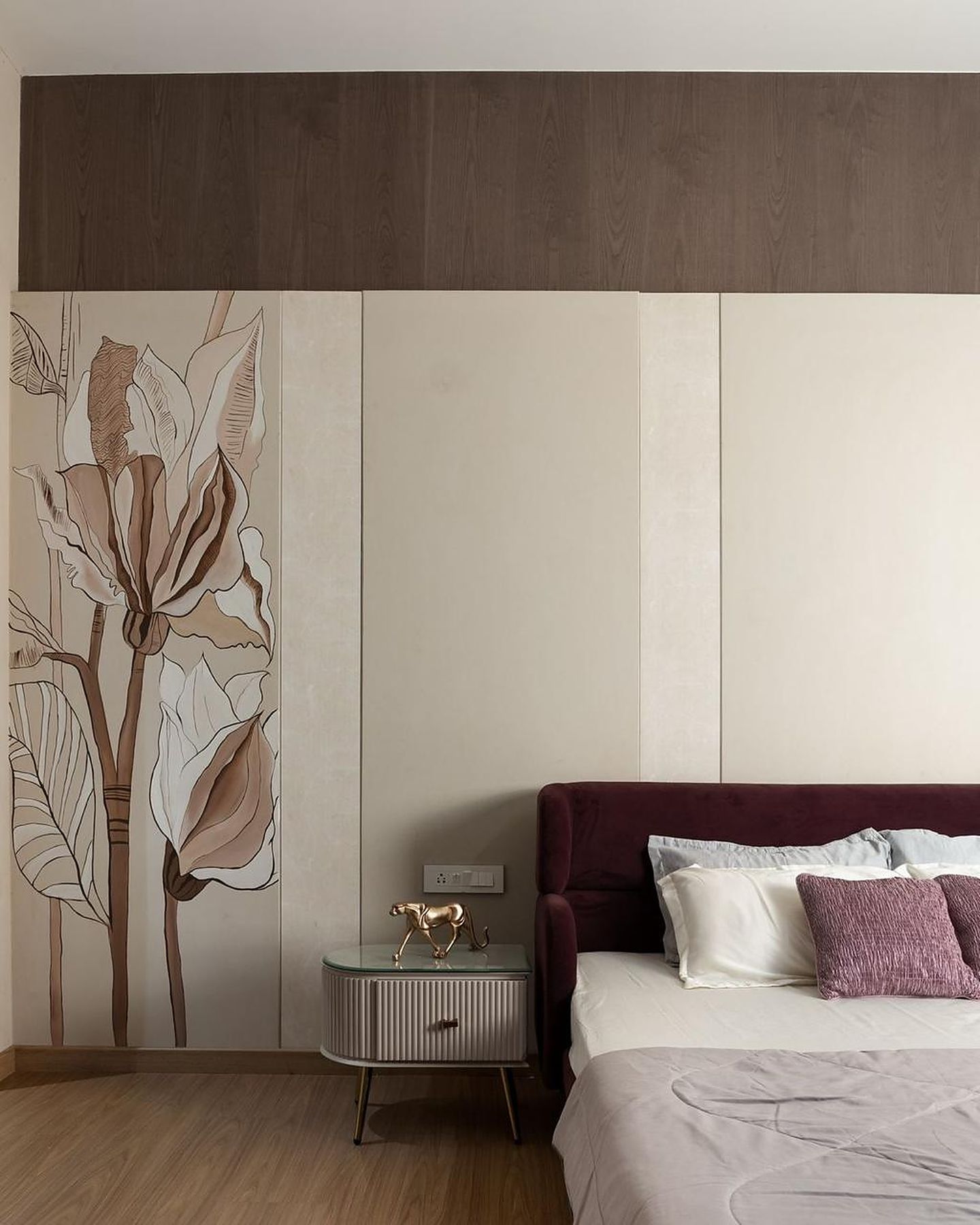 Bedroom with a hand-painted lily mural on pale stone panels and a plum velvet bed